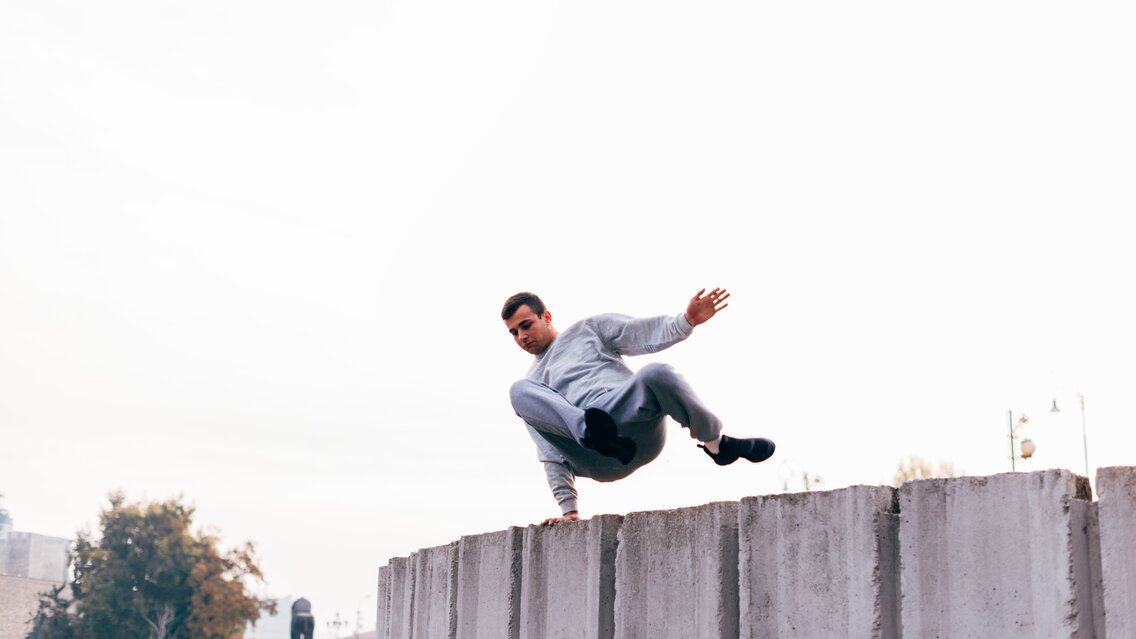 Caucasian man trains parkour while jumping over a high top. | © Â©Dimco - stock.adobe.com